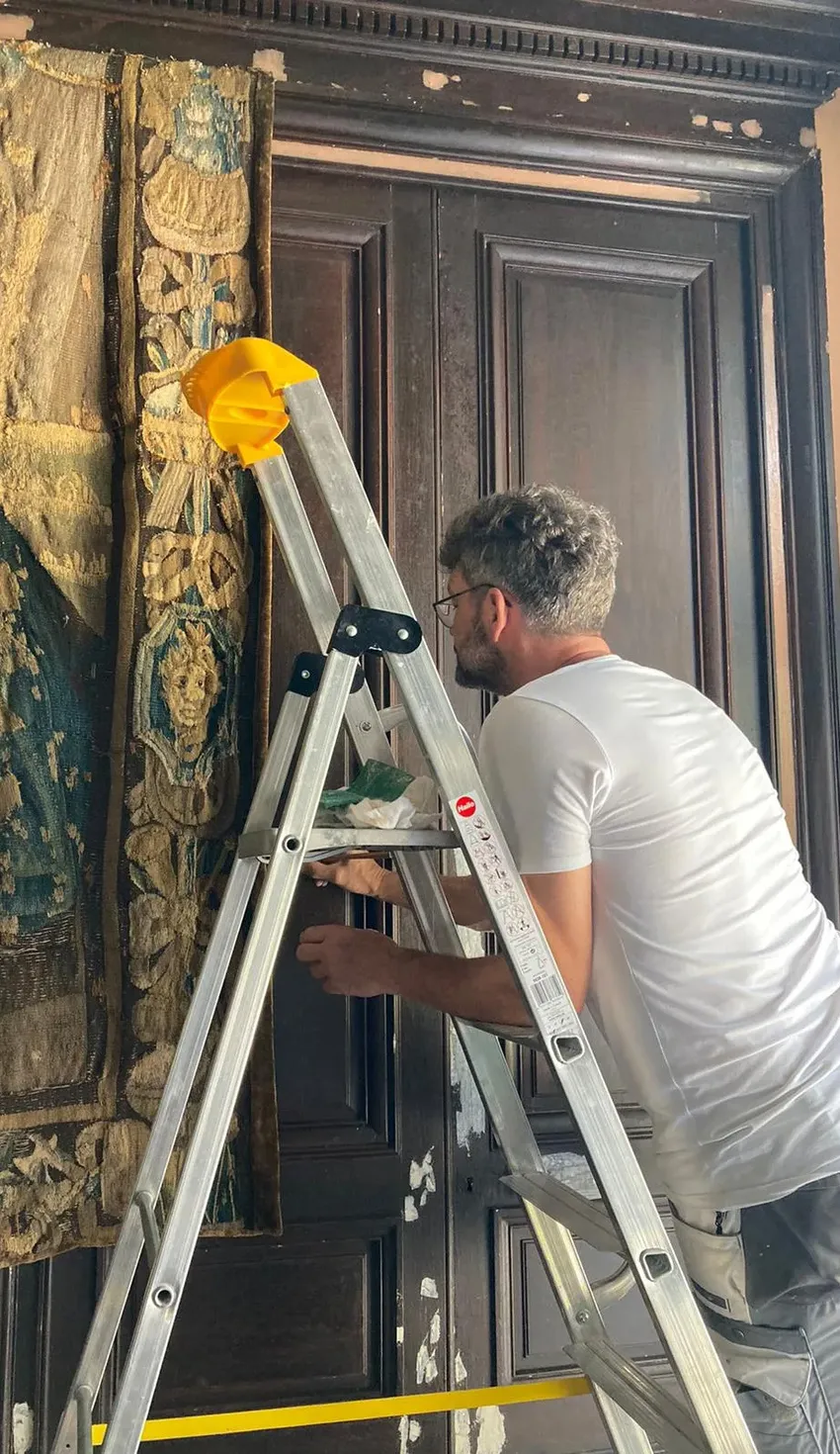 Schilder André Slijkhuis op een ladder bij een monumentale deur
